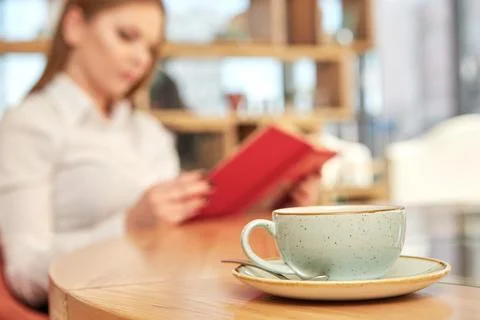 Break from work. Selective focus on a cup on the table business woman reading Stock Photos