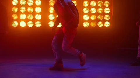 Breakdance guy showing dance elements in spotlight. Dancers performing hip-hop. Stock Photos