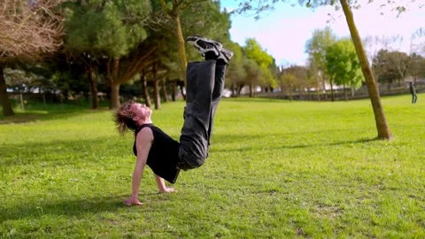 Breakdancer performing acrobatic moves in park Stock Footage 316958082