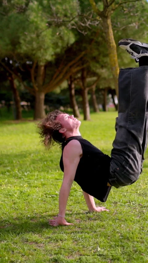 Breakdancer performing acrobatic moves in park Stock Footage 327336088