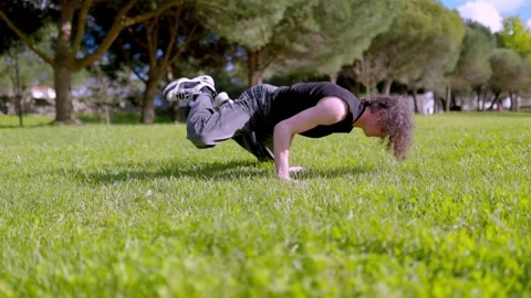 Breakdancer performing acrobatics in a green park Stock Footage 316958188