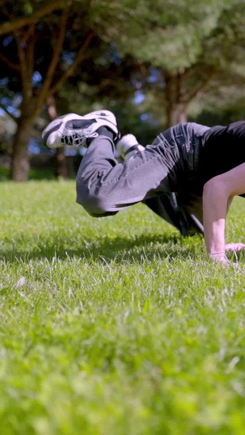 Breakdancer performing acrobatics in a green park Stock Footage 327336347