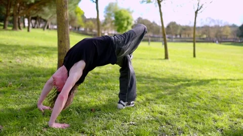 Breakdancer performing backflip in public park Stock Footage 316958099