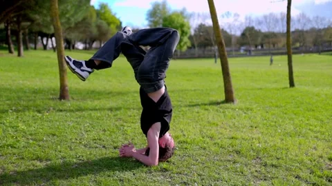 Breakdancer performing headspin and other moves in park Stock Footage 316957981