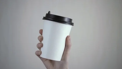 Breakfast and coffee theme: womans's hand holding white empty paper coffee cup Stock-Footage 84771140