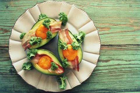 Breakfast. Avocado Egg Boats with crunchy bacon, kale cabbage on wooden backg Foto stock