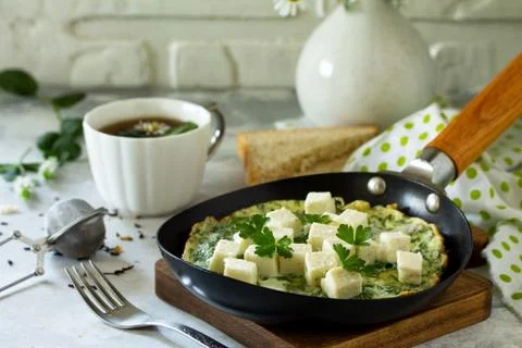 Breakfast background. Fried eggs with spinach, feta cheese on stone table. Stock Photos