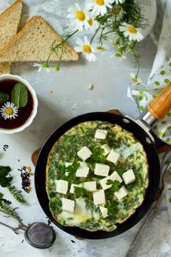 Breakfast background. Fried eggs with spinach, feta cheese on stone table. Stock Photos