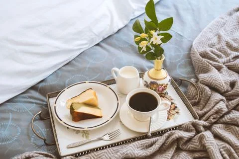 Breakfast in bed slice of Cheesescake with cup of coffee and flower in a tray. Stock Photos