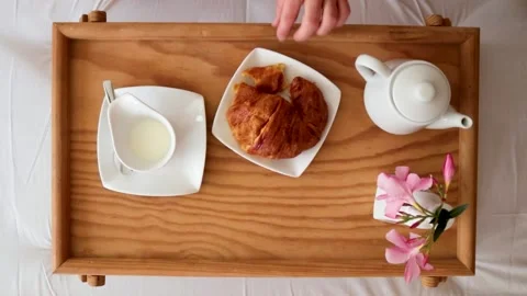 Breakfast in bed, woman's hands holding a piece of croissant, top view. Stock Footage 135421089