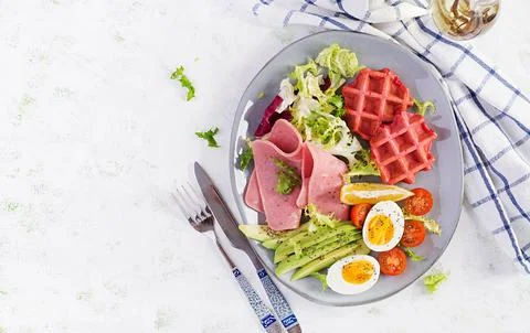 Breakfast with beetroot waffles, boiled egg, ham, tomato and slice avocado .. Stock Photos