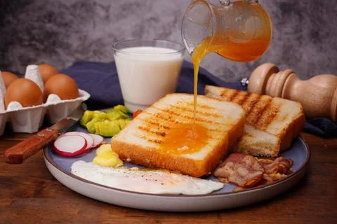 Breakfast bread with fried egg, bacon, pepper, avocado, tomato p Foto stock