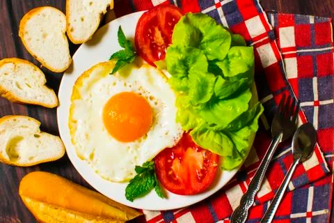 Breakfast with bread, fried eggs, milk and vegetables and fried tomato pieces Stock Photos