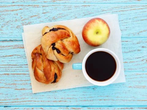 Breakfast with bread roll coffee and apple on baking paper Stock Photos