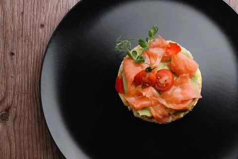 Breakfast, bread toast with scrambled eggs, salmon, avocado and tomatoes Stock Photos