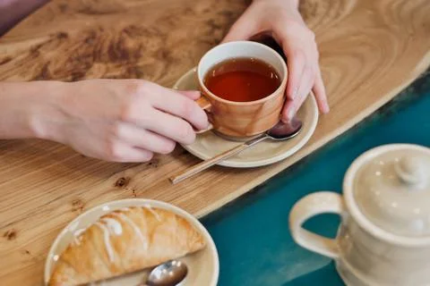 Breakfast in a cafe. Brown ceramic cup with tea and a croissant are on the table Fotos Stock