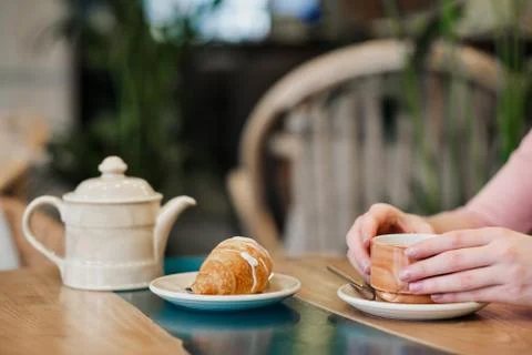 Breakfast in a cafe. Brown ceramic cup with tea and a croissant are on the table Fotos Stock