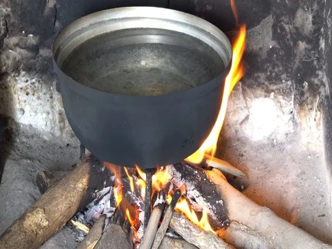 Breakfast in the campaign. Cauldron over the fire. The fire heats the food. Stock Footage 76688254
