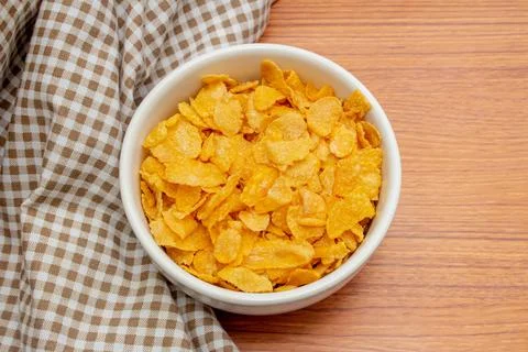 Breakfast cereal concept, Cornflakes in white bowl with gingham cloth on wood Stock Photos