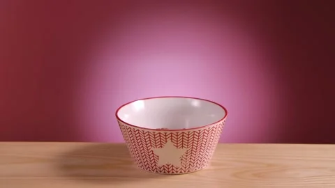 Breakfast cereal in form of chocolate corn balls fall and fill bowl on the table Stock Footage 149133562