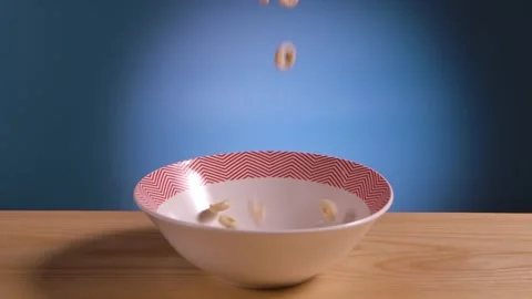 Breakfast cereal in form of corn rings fall and fill bowl on table. Food close Stock Footage 149134349