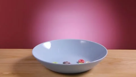 Breakfast cereal in form of multicolored corn rings fall and fill white bowl on Video stock 149133987