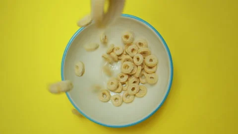 Breakfast cereals falling into cup top view. Yellow background. Camera laowa Video stock 139237721