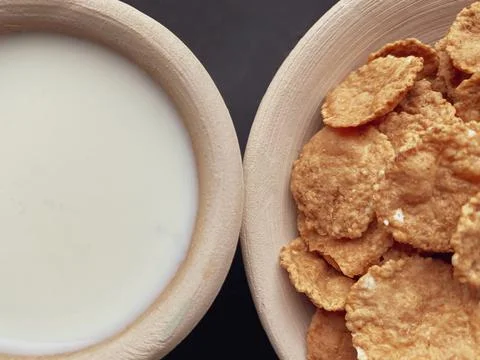 Breakfast cereals, multi-grain flakes in a clay plate and milk in clay cup on Stock Photos