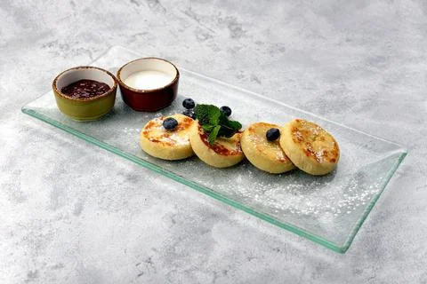 Breakfast, cheesecakes with two sauces and blueberries Stock Photos