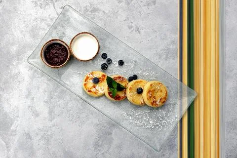Breakfast, cheesecakes with two sauces. mint and blueberries, on a light back Stock Photos