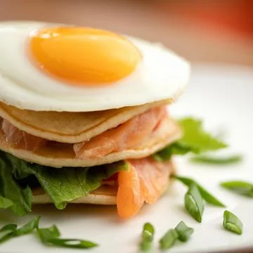 Breakfast, close up. Fried Egg on top of stack of Pancakes and slices of red Stock Photos