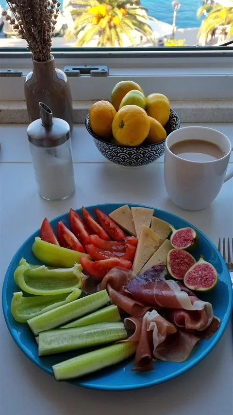 Breakfast with coffee, prosciutto, cheese, figs and mandarins by sea view window Video stock 344964211