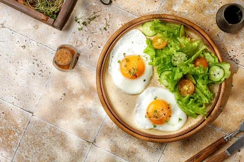 Breakfast concept with fried eggs, micro greens, and salad, cherry tomatoes.. Stock Photos