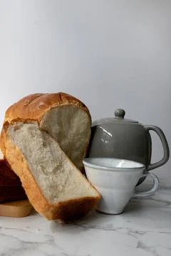 Breakfast Concept, a loaf of white bread, along with a teapot and a cup Stock Photos