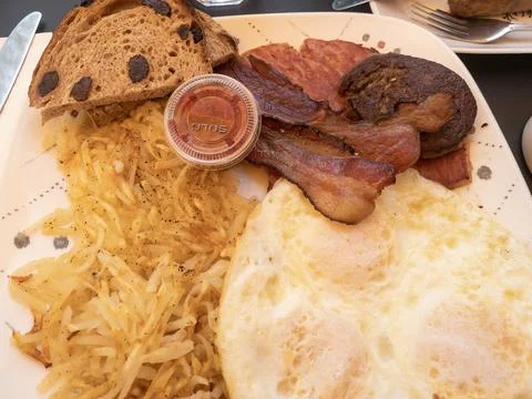 Breakfast consisting of fried eggs, hash browns, meat including ham, bacon,.. Foto stock