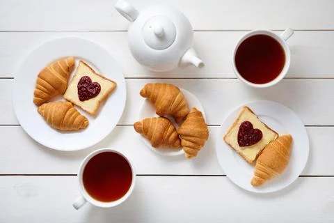 Breakfast for couple with toasts, heart shaped jam, croissants, and tea on white Stock Photos