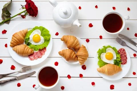 Breakfast for couple on Valentines day with heart shaped fried eggs, salad Stock Photos