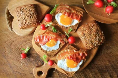 Breakfast , crispy bacon, fried eggs and bread. Sandwiches on cutting board. Foto stock