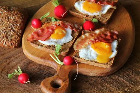 Breakfast , crispy bacon, fried eggs and bread. Sandwiches on cutting board. Stock Photos