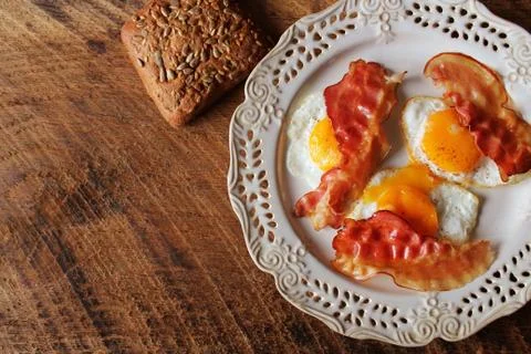 Breakfast , crispy bacon, fried eggs and bread. Sandwiches on white plate. Ru Stock Photos