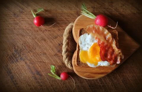 Breakfast , crispy bacon, fried eggs and bread. Sandwich on cutting board. Ru Stock Photos
