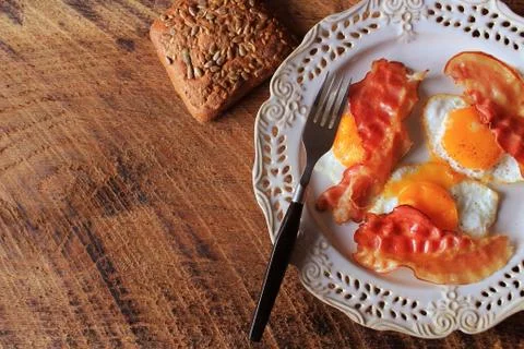 Breakfast , crispy bacon, fried eggs and bread. Sandwiches on white plate. Ru Stock Photos