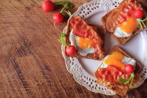 Breakfast , crispy bacon, fried eggs and bread. Sandwiches on white plate. Ru Stock Photos