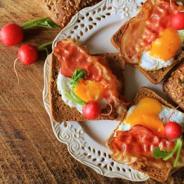 Breakfast , crispy bacon, fried eggs and bread. Sandwiches on white plate. Ru Stock Photos