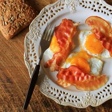 Breakfast , crispy bacon, fried eggs and bread. Sandwiches on white plate. Ru Stock Photos