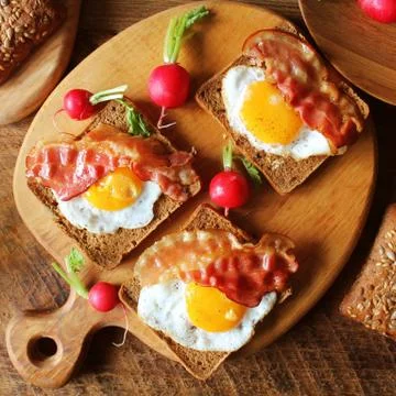 Breakfast , crispy bacon, fried eggs and bread. Sandwiches on cutting board. Stock Photos