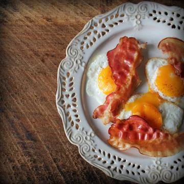 Breakfast , crispy bacon, fried eggs and bread. Sandwiches on white plate. Ru Stock Photos