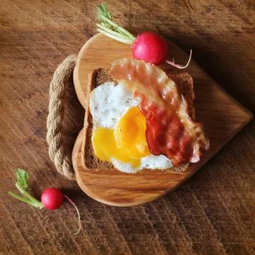 Breakfast , crispy bacon, fried eggs and bread. Sandwich on cutting board Stock Photos