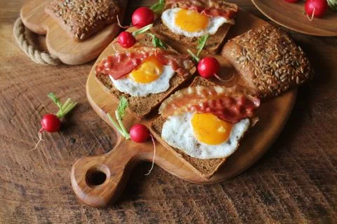Breakfast , crispy bacon, fried eggs and bread. Sandwich on cutting board Stock Photos