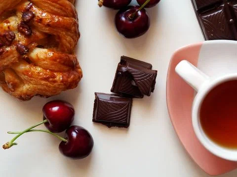 Breakfast with a cup of tea, cherry, bun and chocolate 写真素材